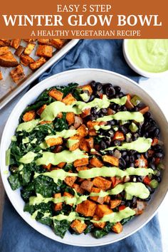 a white bowl filled with black beans, greens and sweet potato wedges next to a pan of green dressing