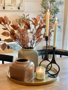 a table with two vases and some candles on top of it next to a candle holder