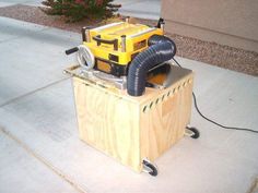 a machine that is sitting on top of a wooden box with a hose attached to it