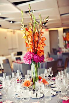 a vase filled with flowers sitting on top of a table covered in plates and glasses