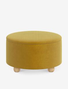 a round ottoman with wooden legs and a mustard colored upholstered cushion on top