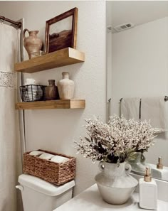 a white toilet sitting under a bathroom mirror next to a sink and a shower curtain