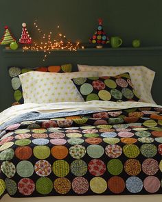 a bed covered in lots of pillows and blankets next to a shelf with christmas lights