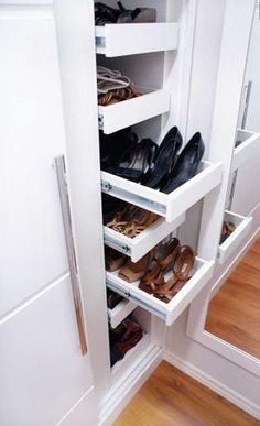 an open closet filled with lots of shoes on top of wooden floor next to white walls