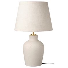 a white table lamp with a beige shade on the base and a black cord attached to it