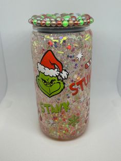 a glass jar filled with lots of glitter and santa's hat on the lid