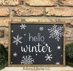 a black and white sign that says hello winter with snowflakes on it in front of a brick wall