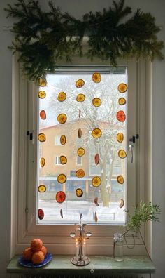 a window decorated with oranges and pine cones