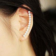 a close up of a person wearing a pair of ear cuffs with diamonds on them