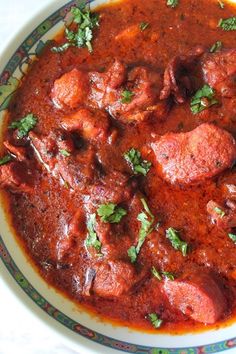 a bowl filled with meat and sauce on top of a table