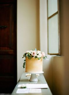 a cake sitting on top of a table next to a window with flowers in it