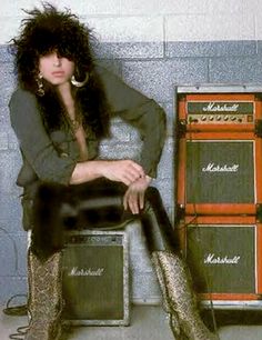 a woman sitting on top of a chair next to two amps