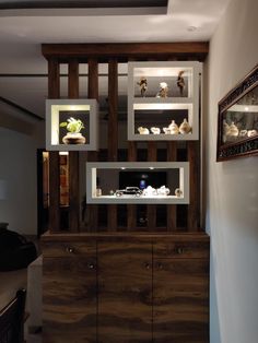 a wooden cabinet with glass shelves above it and other items on the wall behind it