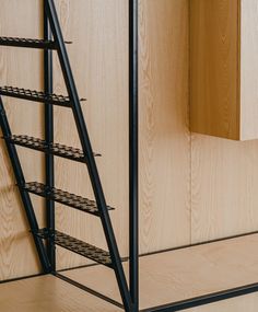 there is a black metal shelf next to the wooden wall with shelves on each side