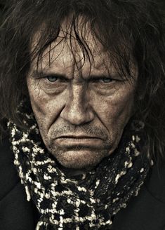 an old man with long hair wearing a scarf