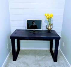 a table with a vase and flowers on it next to a framed photo in the corner