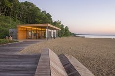 a wooden walkway leading to the beach with a glass building on it's side