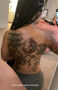 a woman with tattoos on her back taking a selfie