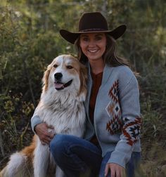 a woman in a cowboy hat sitting next to a white and brown dog on the grass