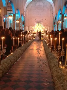 the aisle is lined with candles and people are standing in front of them on either side