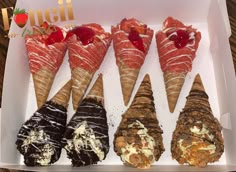 four different types of ice cream cones in a white box with strawberries on top