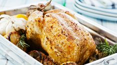 a roasted turkey in a white dish with lemons and rosemary