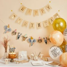 a birthday party set up with balloons, streamers and animal themed decorations on a table