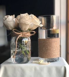 two vases filled with white roses sitting on top of a table