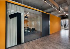 an empty office with yellow walls and black accents on the wall, along with sliding glass doors