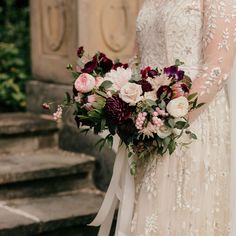 a bride holding a bouquet of flowers in her hand and standing next to some steps