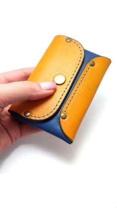 a woman's hand is holding a small yellow and blue wallet with buttons on it