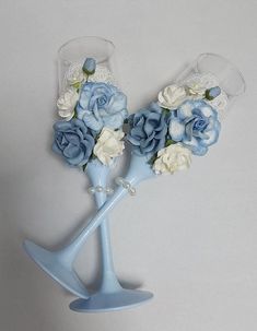 two blue vases with white and blue flowers in them on a gray background,