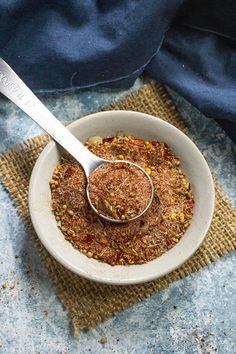 a white bowl filled with granola on top of a blue table cloth next to a spoon