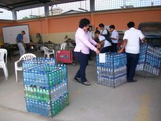 several people are standing around with water bottles in front of them and one person is pushing a cart full of bottled water