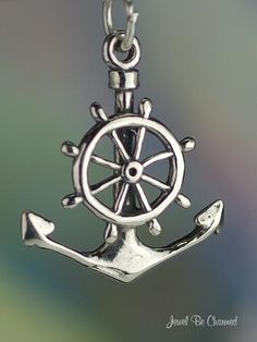 an anchor and wheel pendant is shown on a chain with a blurry blue background