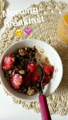 a bowl of cereal with strawberries in it and a glass of orange juice on the side