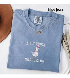 a blue t - shirt that says silly goose nurse club next to a brown hat