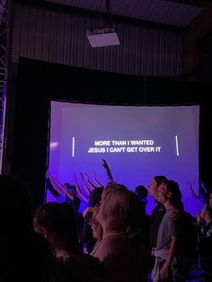 a group of people standing in front of a projection screen with their hands up to the sky