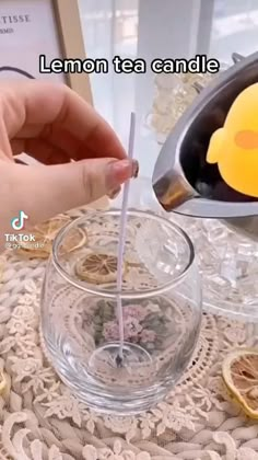 someone is pouring tea into a glass with lemons on the table next to it