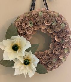 a wreath made out of rolled paper flowers hangs on the wall next to a pair of scissors