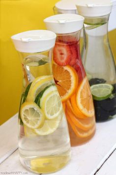 three pitchers filled with different types of fruit