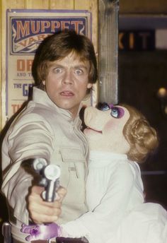 a man holding a stuffed animal in front of a puppett house sign with the words muppet on it