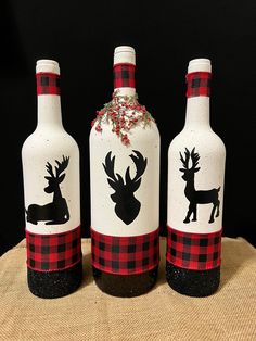 three wine bottles decorated with black and red flannel, deer and snowflakes