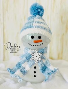 a small snowman with a blue hat and scarf