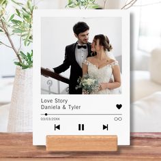 a photo frame with a couple on it next to a vase filled with flowers and greenery