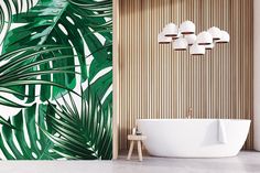 a white bath tub sitting next to a wall with green leaves on it and three lights hanging from the ceiling