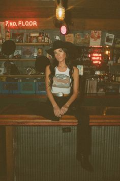 a woman sitting on top of a wooden bar