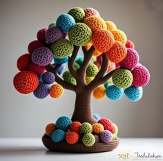 a crocheted tree with multicolored balls on it's trunk and branches