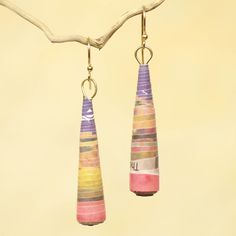 pair of colorful earrings hanging from branch on beige background with tree branch in the foreground