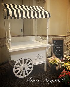 a white cart with black and white striped awning next to some tulips